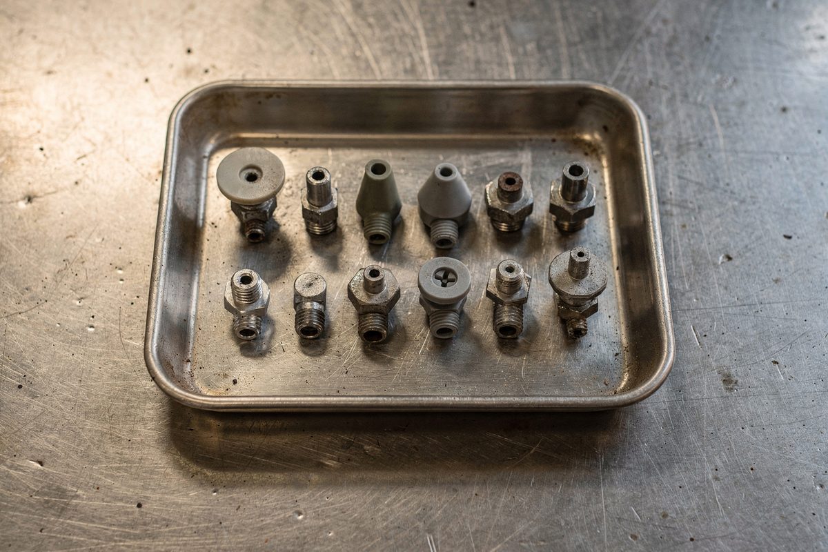 A tray of flat-fan and cone spray nozzle tips sorted by size